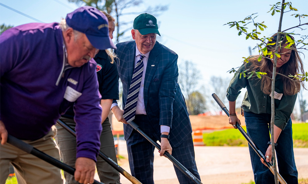 An image showing President Jim planting a tree