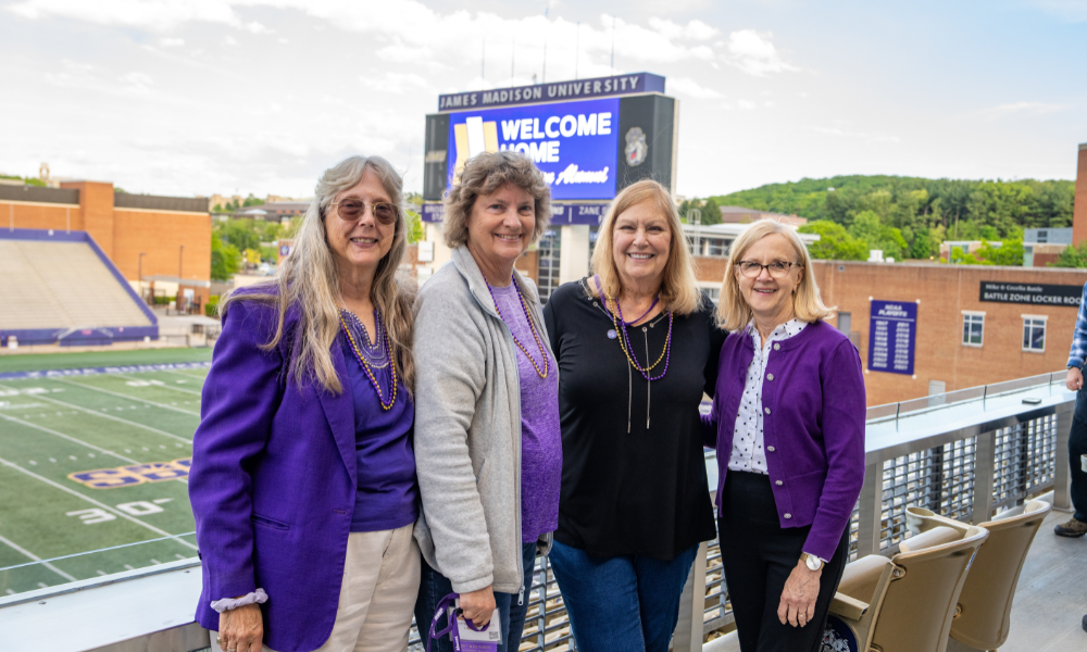 Janice and her three friends to her right posing for the camera with Bridgeforth stadium in the background.