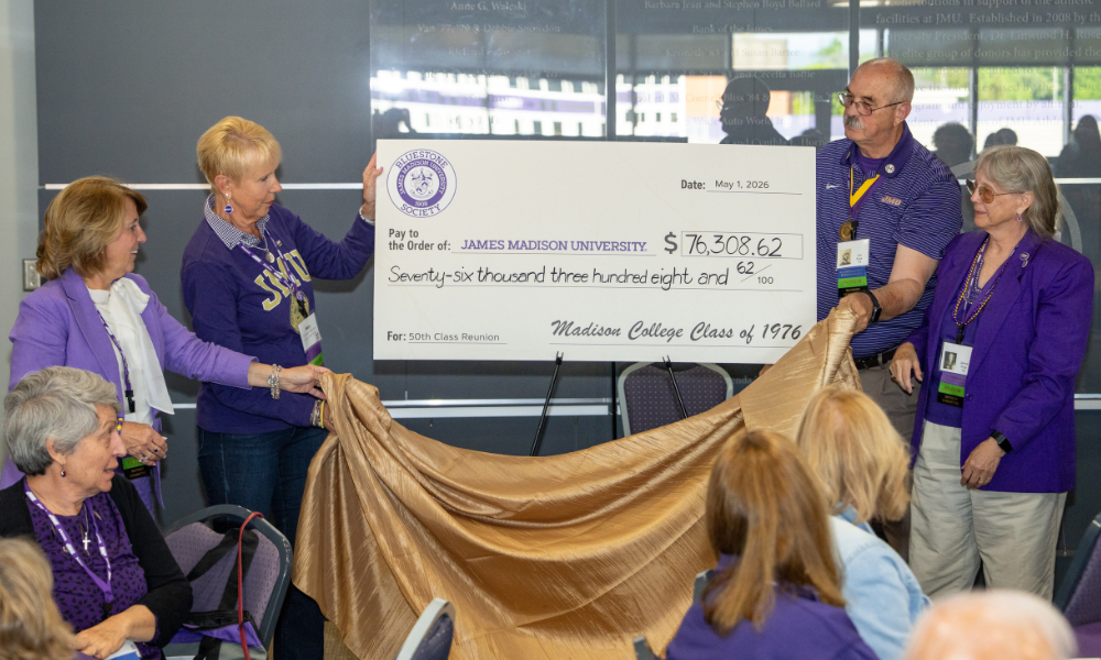 IMage of 4 committee members surrounding the check that states $76,308.62 paid to the order of James Madison University by Madison Collage Class of 1976 for 50th Class Reunion. The members are unveiling the large check.