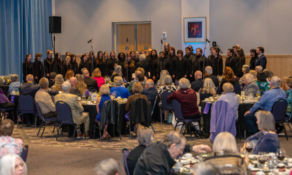 round tables with alums all looking at Madison Singers actively singing in Festival Ballroom.