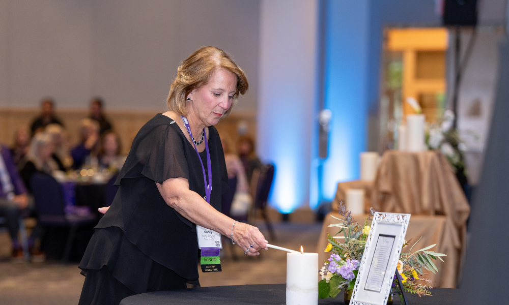 Nancy Moyers lighting a candle set on a table 