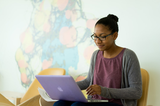 Jesmine Roberts-Torres studies with her laptop near the DNA mural in the JMU Bioscience Building