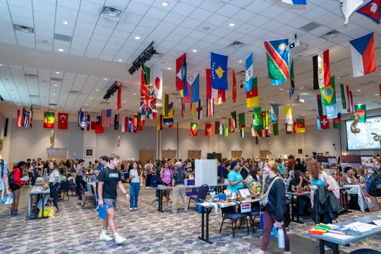 Students at Study Abroad Fair with country flags from the ceiling