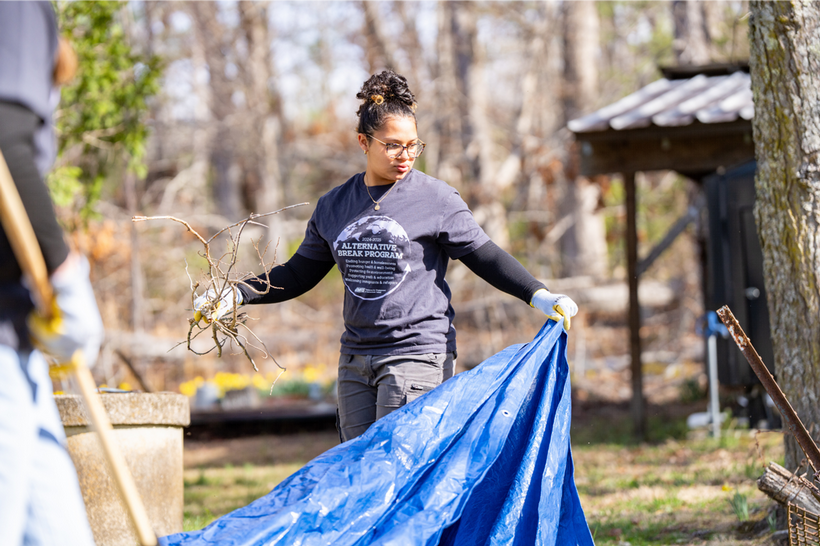 Student on Alternative Break picking up twigs
