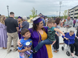 woman in grad gown with 2 little boys