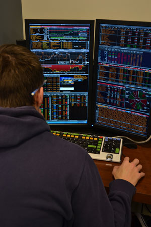 student looking at computer screens with financial data and charts.