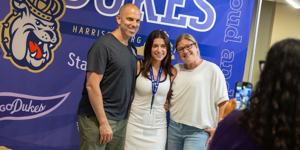 A father and mother posing with their daughter at Summer Orientation.