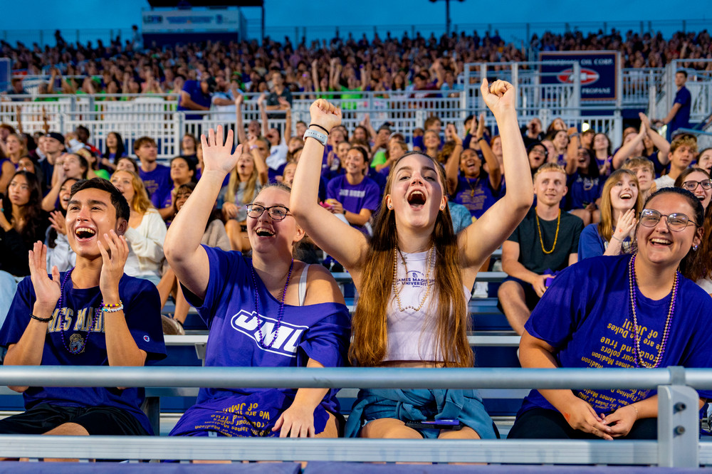 Two students with their hands in the air and cheering.