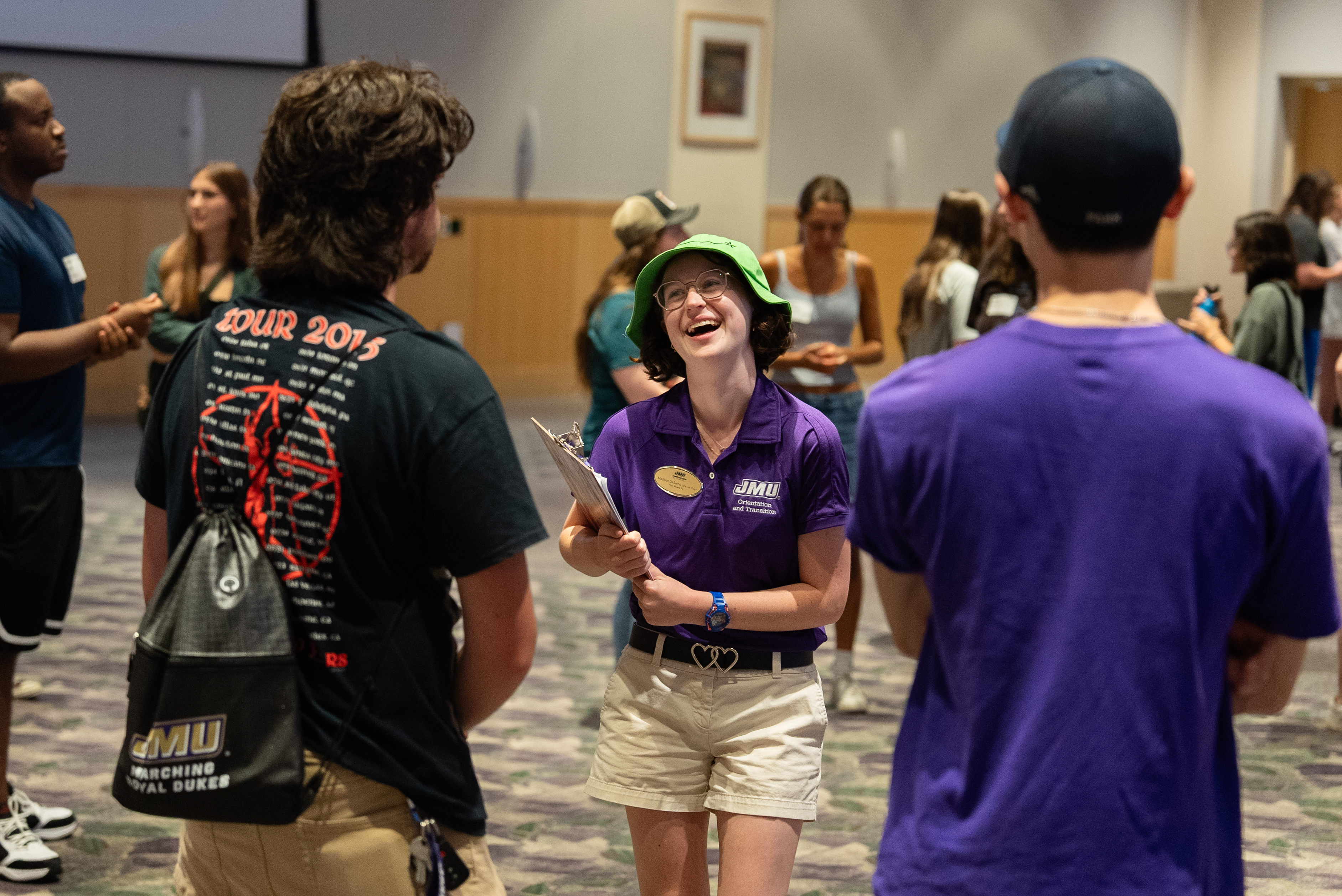 Student in a purple polo talking with two other students engaging them in conversation.