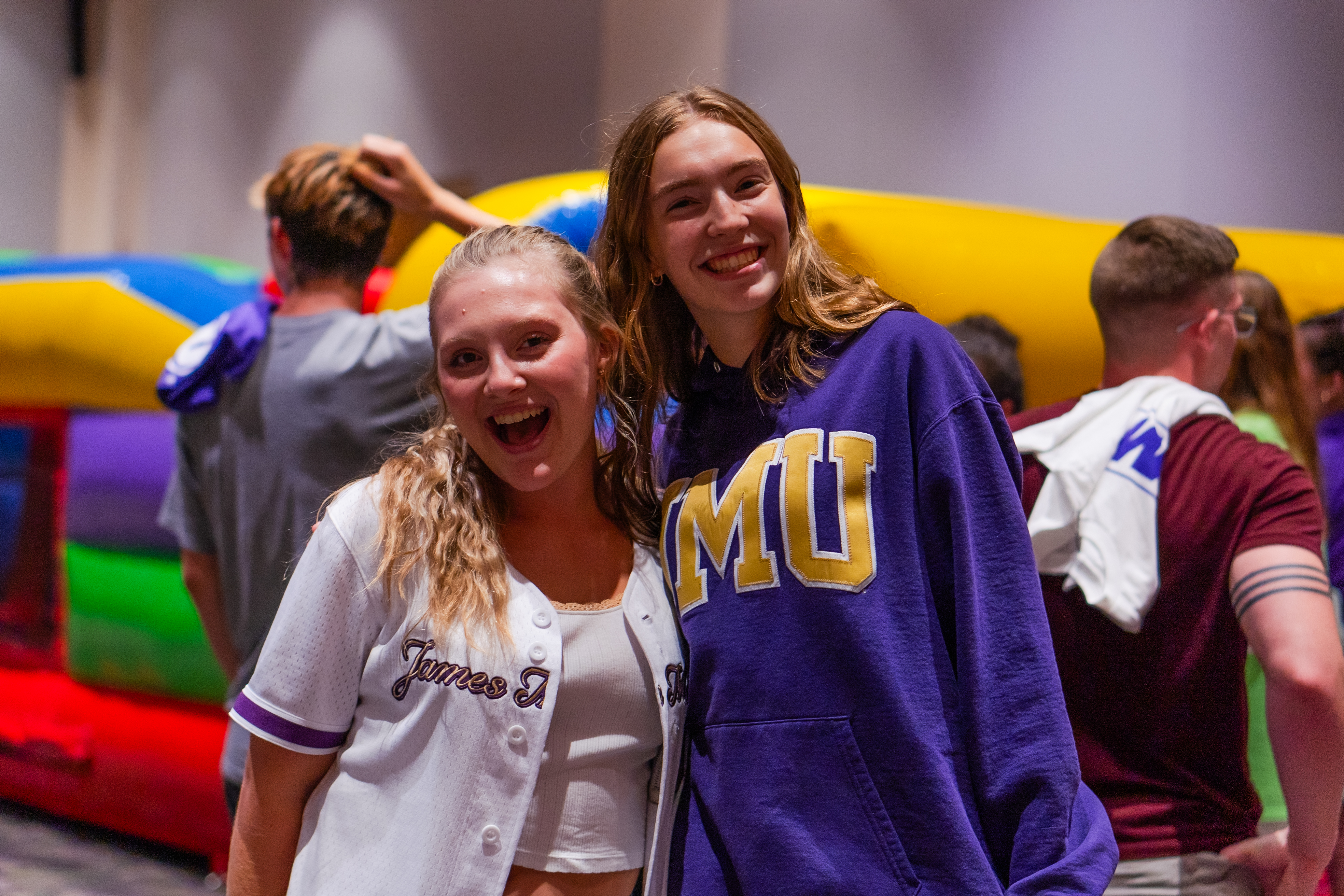 Two students in JMU gear smiling for a photo.