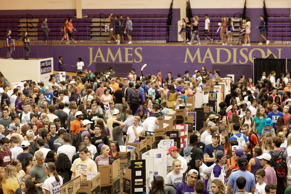 a large throng of students making their way through Student Org Night in the convocation center while the numerous clubs show off posters and pictures of what its like to be a member