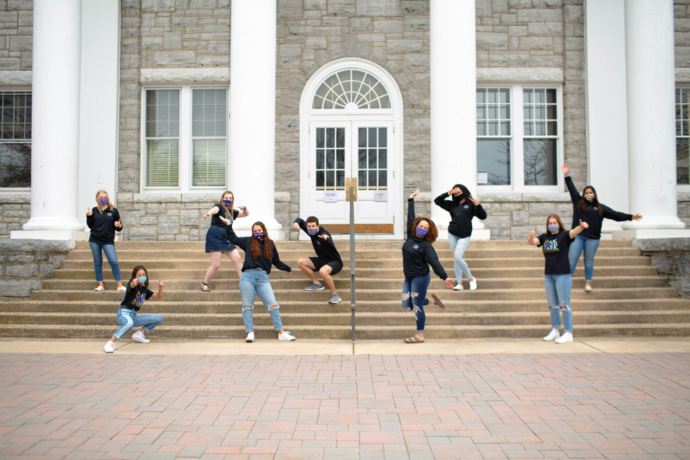 9 members of Make Your Mark On Madison pose dynamically spread across the steps of Wilson Hall