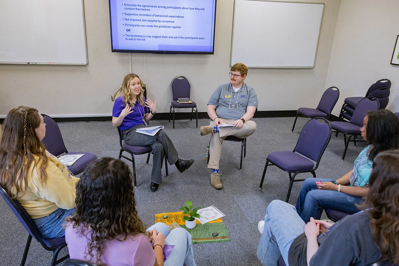 6 people sitting in a circle looking enganged