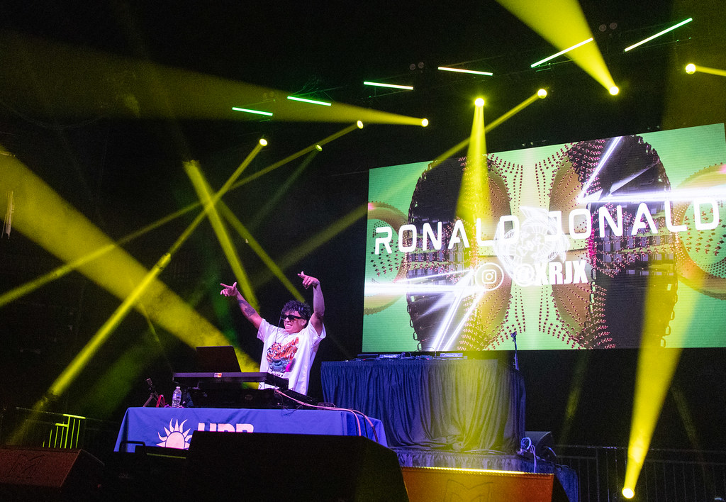 D.J. on stage at a concert with his hand up