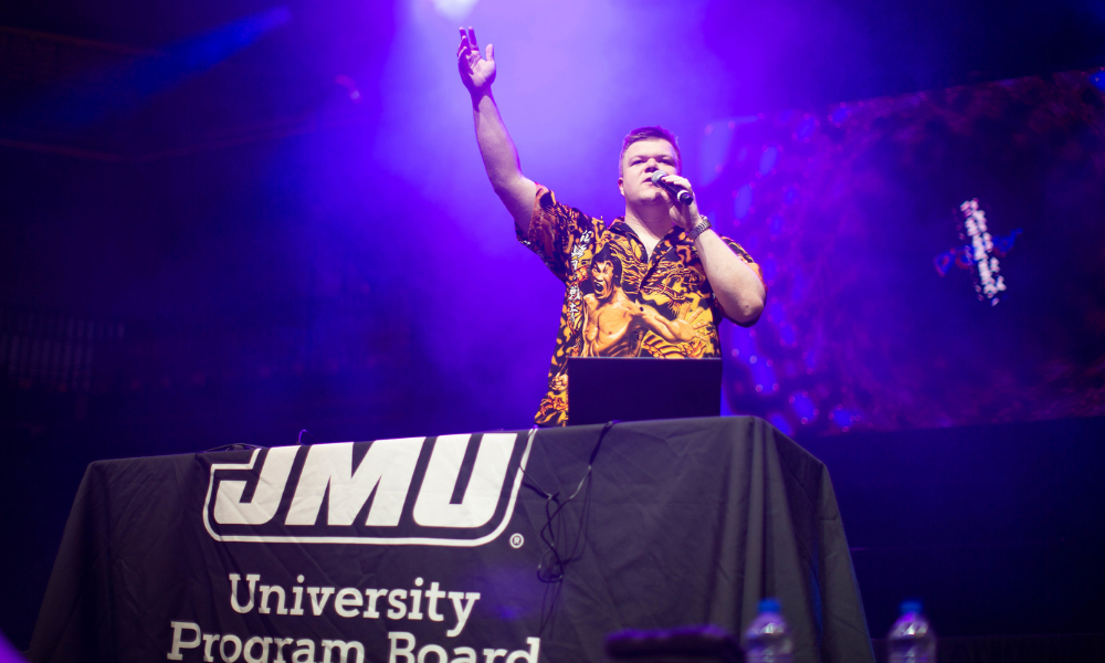 D.J. on stage at a concert with his hand up