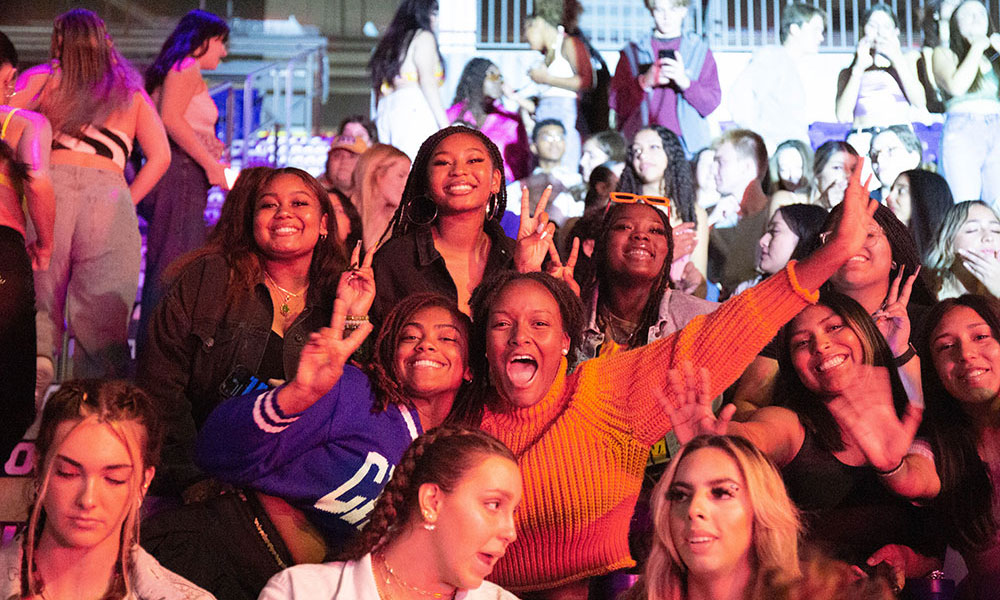 Five women posing at a concert in the crowd