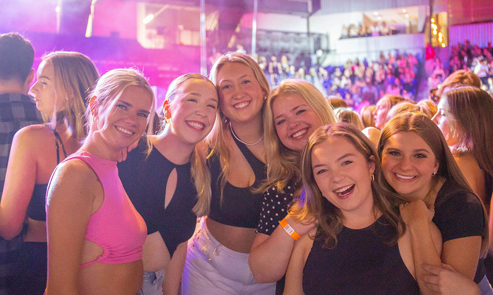 Six women posing together at a concert