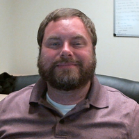 Bryan - Smiling man with brown hair and beard, 