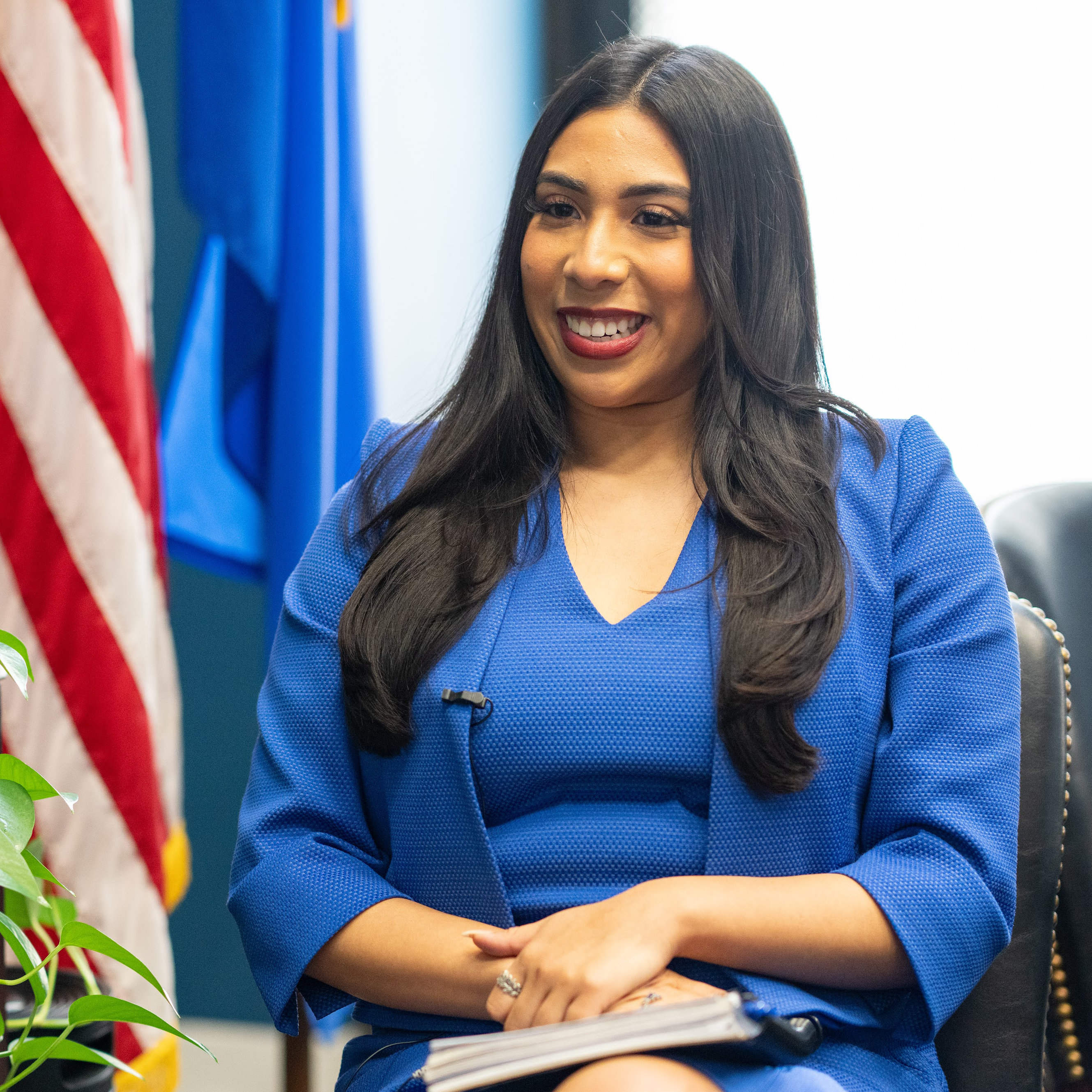 Smiling person sitting in front of an American flag.