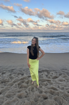 Dance instructor standing on the beach smiling with hand on hip