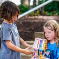 Children engaged in a creative activity, crafting a colorful structure from various materials while seated on outdoor steps.