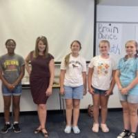A group of six students, standing together with a Aubrey Urbanowicz in a classroom setting, posing for a photo.