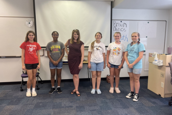 A group of six students, standing together with a Aubrey Urbanowicz in a classroom setting, posing for a photo.