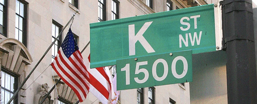 Picture of k street sign in Washington DC with the american flag in the background