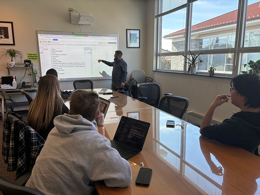 Lab Director meeting with students to explain a coding assignement during their weekly lab meeting.