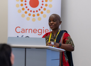 A woman with a shaved head speaking behind a podium