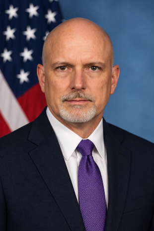 Image of man wearing suit standing in front of American flag