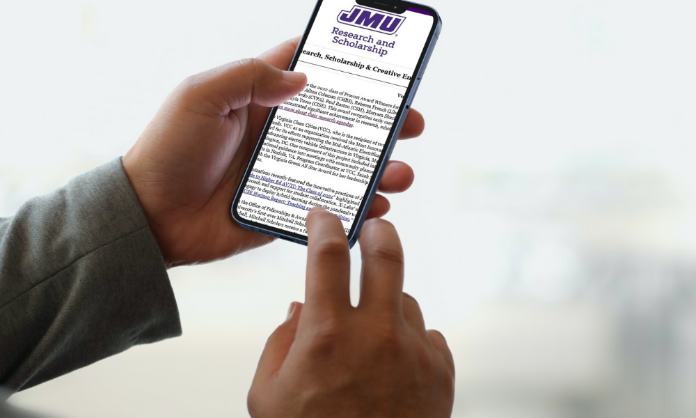 Close up of a hands holding a smart phone displaying text from the JMU Research & Scholarship newsletter