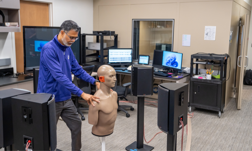 JMU faculty manipulating a full-body auditory model in the middle of a working lab