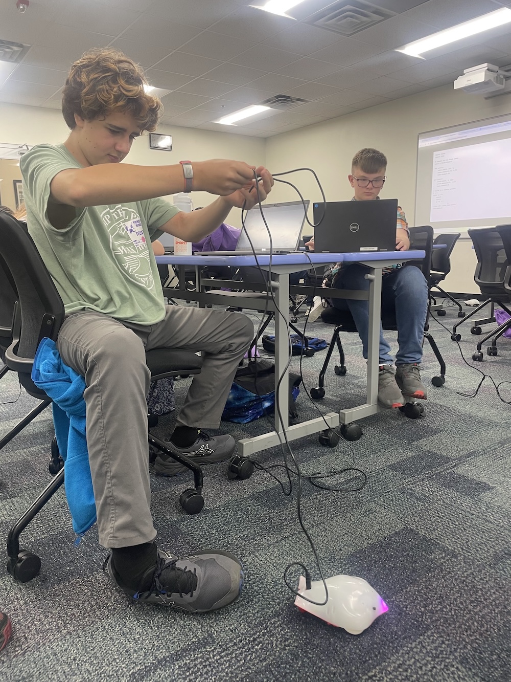 Student untangels the cable connected to a finch robot.
