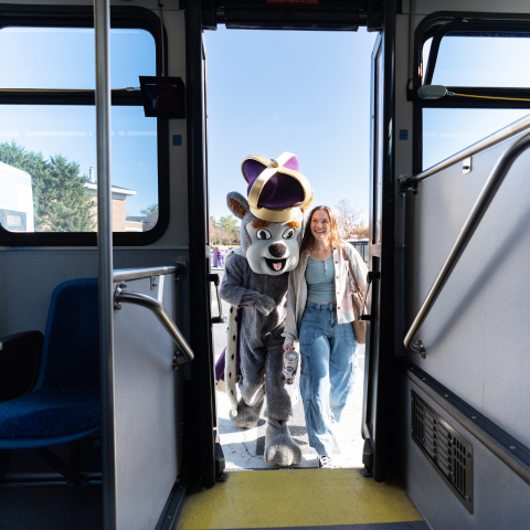 JMU Duke Dog mascot and student board the campus bus.