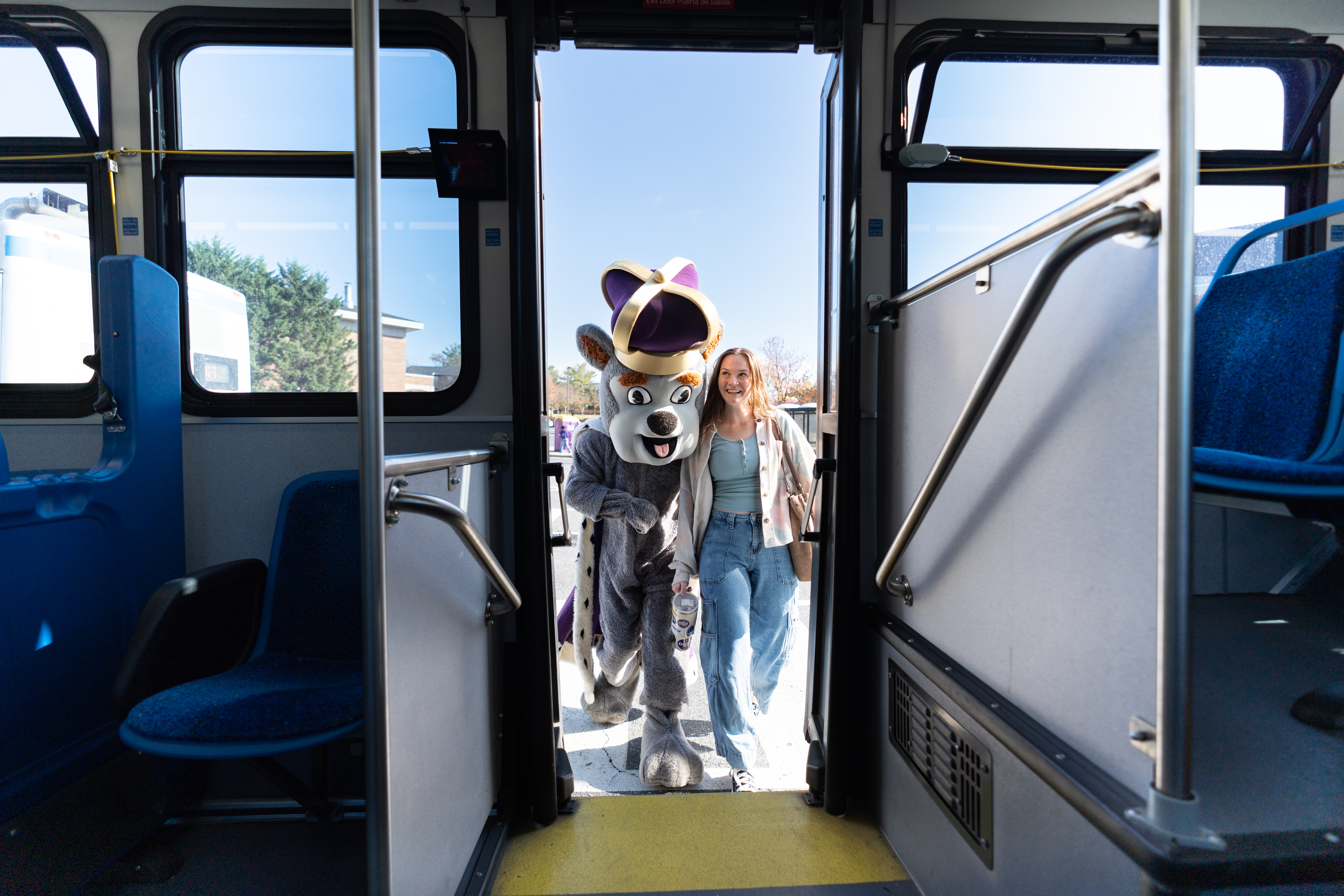 student and school mascot getting on the bus