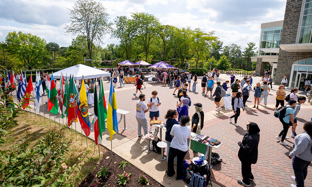 Students gather outside with flags of various countries