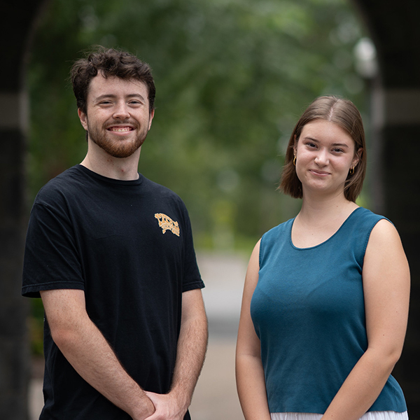 Two smiling student employees stand side by side in an outdoor setting