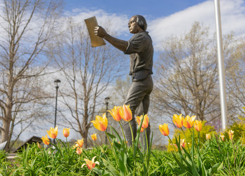 spring flowers in focus in front of the east campus James Madison statue symbolizing growth, renewal and connection to campus